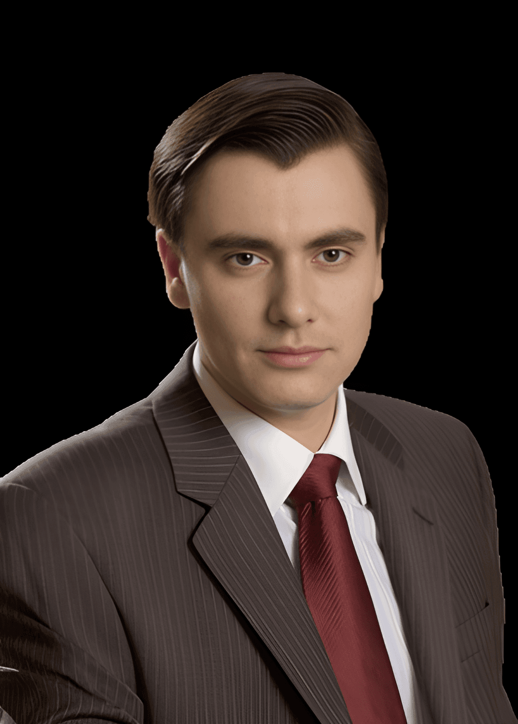 Individual wearing a dark pinstripe suit, white shirt, and red tie.